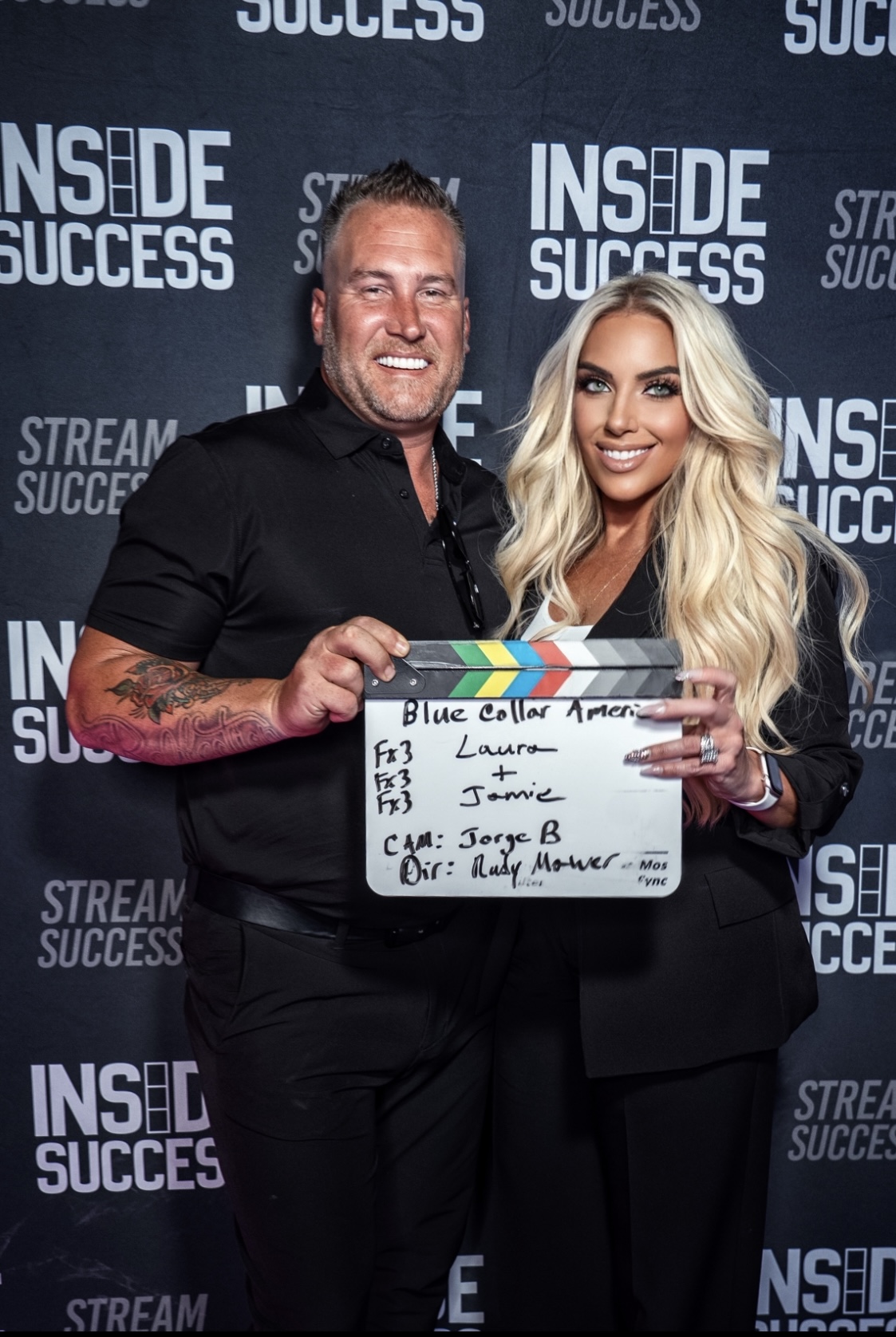 Laura Roark and Jamie Hale holding a Blue Collar America production clapperboard reading 'Laura + Jamie' at the Inside Success studio